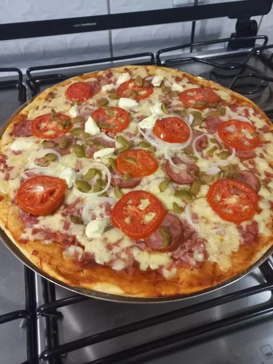 Pizza de pizzaria feita em forno comum de fogão, borda alta e recheada